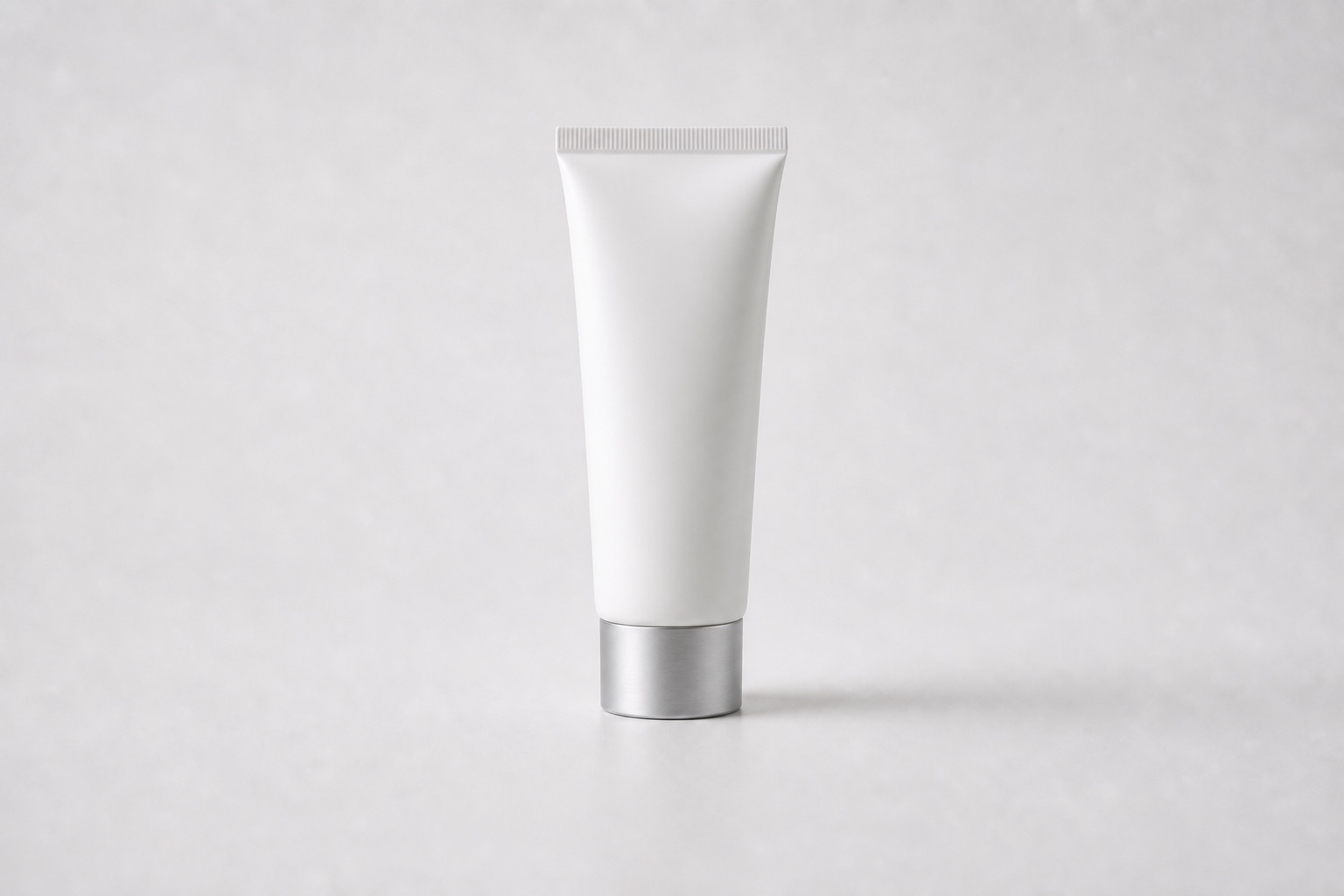 Single matte white cosmetic tube with a silver cap on a clean white studio background