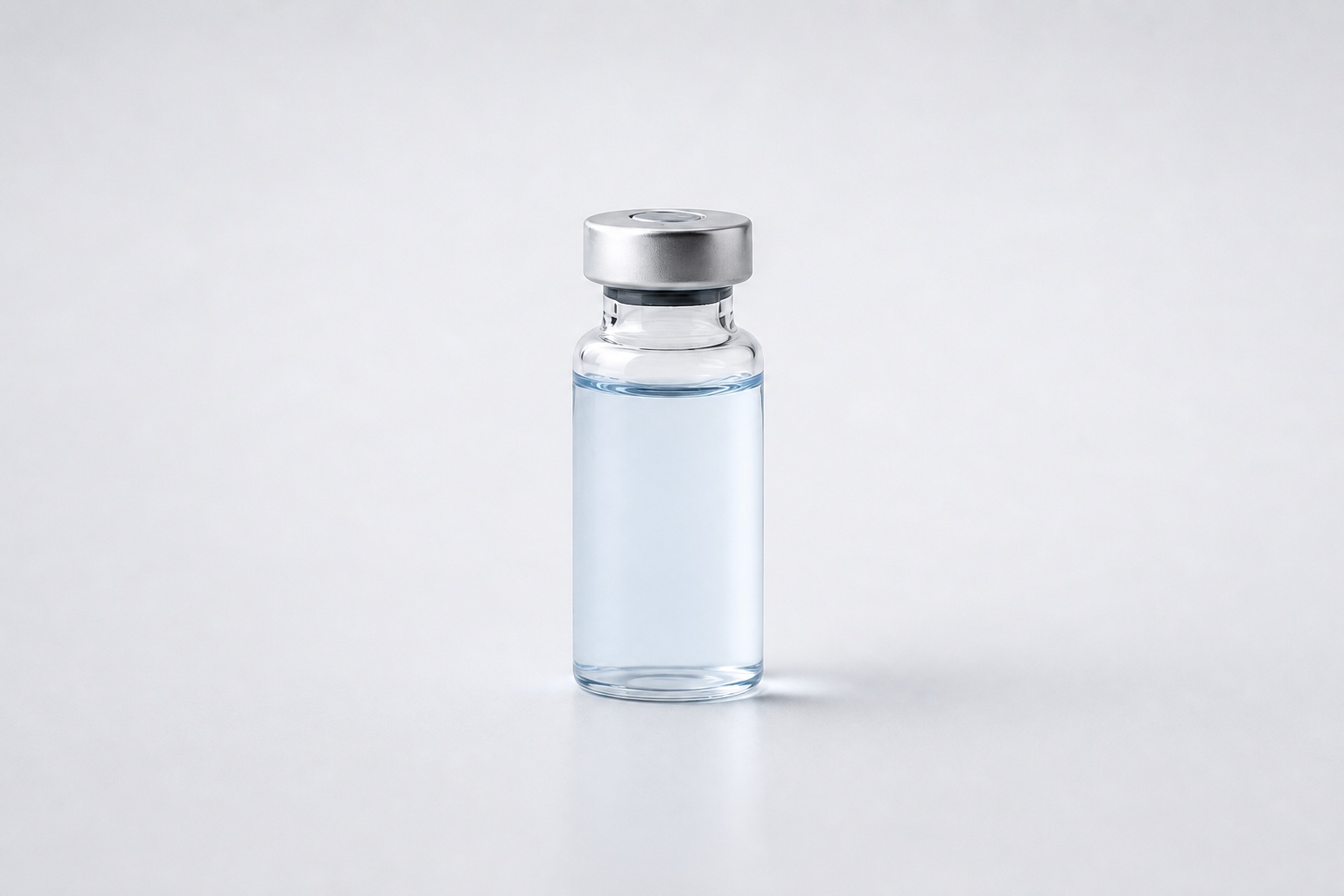 Single clear pharmaceutical vial with pale blue liquid on a clean white studio background
